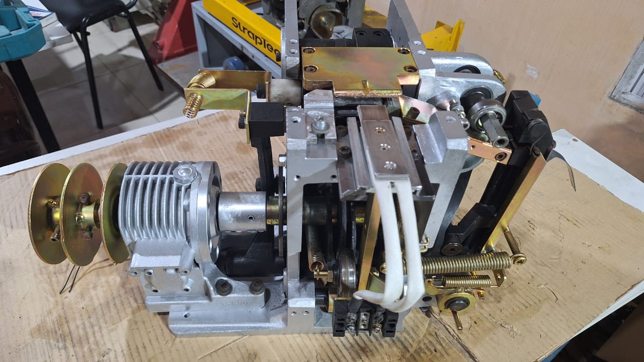 Mecanismo de flejado con motor y poleas sobre una mesa de trabajo